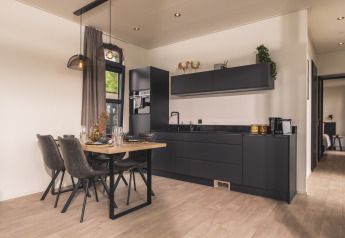 Cocina moderna y comedor en el lodge Villa Maritiem, con muebles negros y decoración elegante y contemporánea.