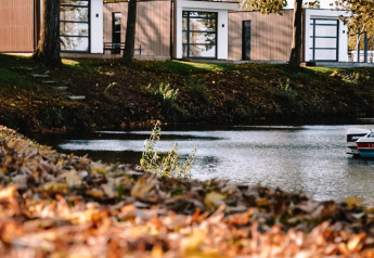 Lodge moderno junto al lago, Villa Maritiem en MarinaPark Bad Nederrijn, rodeado de árboles en Países Bajos.