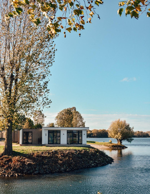 Lodge moderno sul lago al MarinaPark Bad Nederrijn, Paesi Bassi, immerso tra alberi e acqua serena.