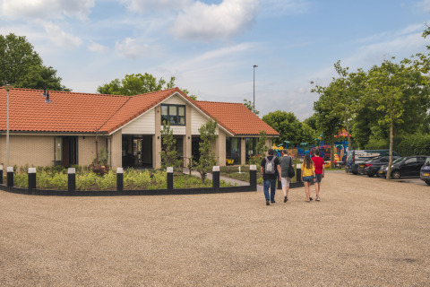Quattro persone si avvicinano a Villa Maritiem al MarinaPark Bad Nederrijn nei Paesi Bassi vicino a un parco giochi.