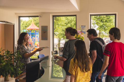 Una famiglia effettua il check-in alla Villa Maritiem, MarinaPark Bad Nederrijn, Paesi Bassi, parco giochi fuori.