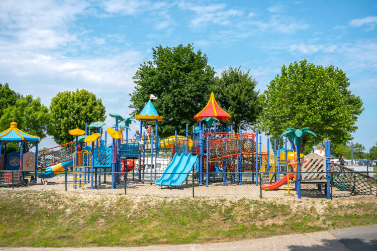 Bunte Spielplatzanlage mit Rutschen und Klettergerüsten bei Villa Maritiem im MarinaPark Bad Nederrijn, Niederlande.