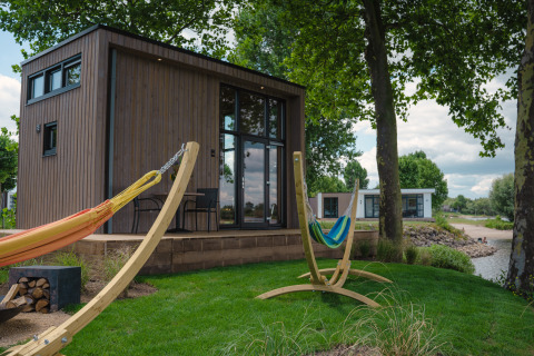Buitenaanzicht met hangmatten en een Tiny River House in MarinaPark Bad Nederrijn, Nederland.