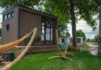 Outdoor view with hammocks and a Tiny River House at MarinaPark Bad Nederrijn in the Netherlands.