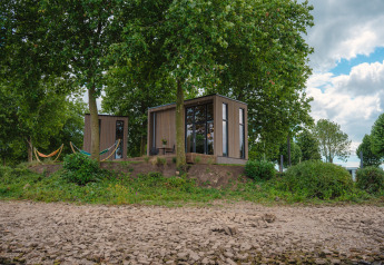 Tiny River House at MarinaPark Bad Nederrijn in the Netherlands, surrounded by trees, hammocks, and stones