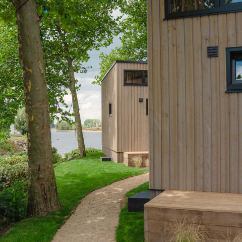 Wandelpad tussen houten tiny houses aan het water in MarinaPark Bad Nederrijn, Nederland.