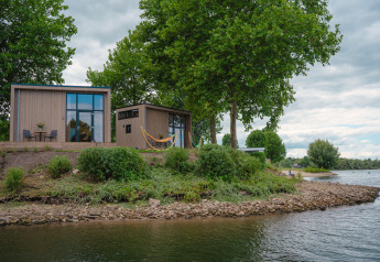 Tiny River House am Wasser im MarinaPark Bad Nederrijn, Niederlande, umgeben von Bäumen und Natur.