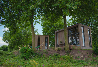 Moderne tiny house aan MarinaPark Bad Nederrijn in Nederland, omgeven door bomen en natuur.