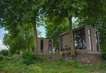 Contemporary tiny house at MarinaPark Bad Nederrijn, Netherlands, nestled among trees and natural greenery.