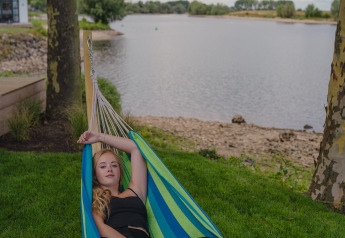 Jeune femme se détendant dans un hamac au bord de la rivière à Tiny River House, MarinaPark Bad Nederrijn, Pays-Bas.