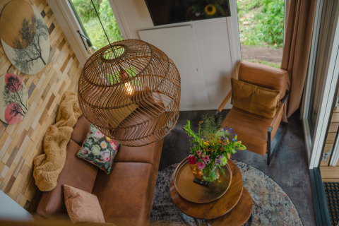 Zicht op de woonkamer van Tiny River House bij MarinaPark Bad Nederrijn met zetel en verse bloemen.