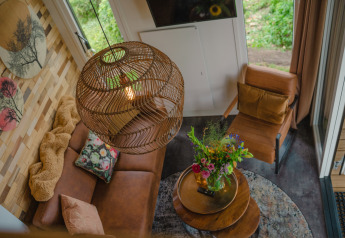 Vista del salón de Tiny River House en MarinaPark Bad Nederrijn con sofá de cuero y flores frescas.