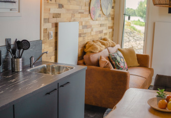 Hyggelig stue og køkkenområde med trævæg, moderne indretning og udsigt i Tiny River House, MarinaPark Bad Nederrijn.