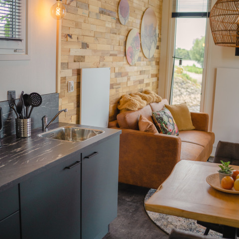 Spazio soggiorno e cucina accogliente con pareti in legno nel Tiny River House a MarinaPark Bad Nederrijn.