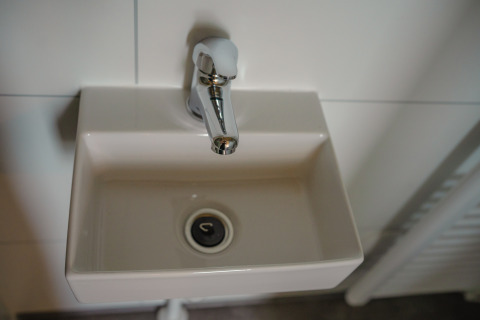 Pequeño lavabo con grifo en el baño de Tiny River House en MarinaPark Bad Nederrijn, Países Bajos.