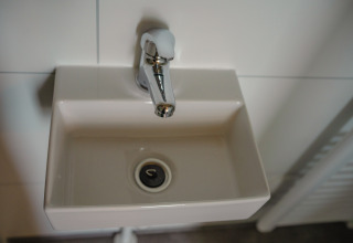 Pequeño lavabo con grifo en el baño de Tiny River House en MarinaPark Bad Nederrijn, Países Bajos.