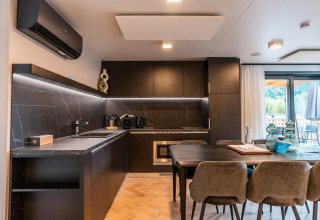 Cocina moderna y comedor en la Wulfenia Waterfront lodge en Ossiacher See, Austria, con detalles en mármol oscuro.