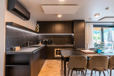 Cocina moderna y comedor en la Wulfenia Waterfront lodge en Ossiacher See, Austria, con detalles en mármol oscuro.