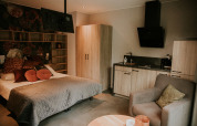 Interior de loft de lujo tiny house en Camping Si-Es-An, Países Bajos, con cama, cocina y sillón.
