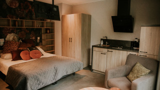 Luxury loft tiny house interior at Camping Si-Es-An, Netherlands, showing bed, kitchenette, and armchair.