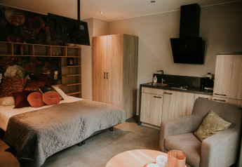 Interno di una tiny house loft di lusso con letto, angolo cottura e poltrona al Camping Si-Es-An, Paesi Bassi.