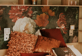 Interior de un loft de lujo en Camping Si-Es-An, Países Bajos, con fondo floral y cojines decorativos.