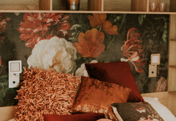 Luxury loft interior at Camping Si-Es-An, Netherlands, with floral wallpaper and decorative cozy pillows.