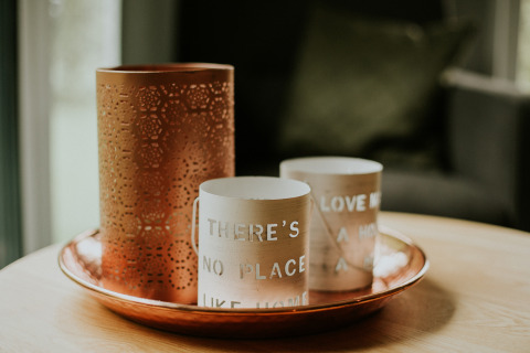 Vassoio decorativo con portacandele rame e beige su un tavolo in un loft di lusso nei Paesi Bassi.