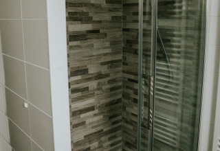 Modern shower with glass door and wood-style wall tiles in the Luxury Loft at Camping Si-Es-An, Netherlands.