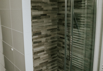 Moderne douche met glazen deur en houtlook tegels in de Luxury loft bij Camping Si-Es-An, Nederland.