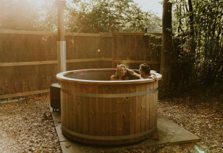 Pareja disfruta de un jacuzzi de madera en el Luxury Loft tiny house de Camping Si-Es-An, Países Bajos.