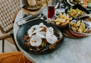Comida de lujo en mesa redonda con papas fritas, ensalada y crujientes en Camping Si-Es-An, Países Bajos.