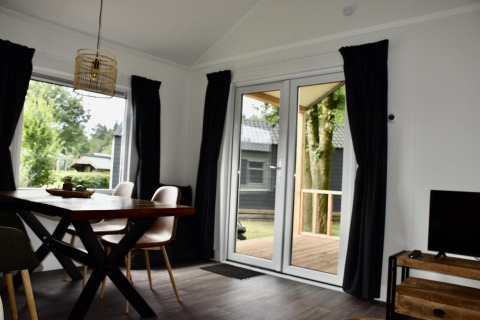 Modern chalet living room with dining area and terrace view at Beach house, Camping 't Veld, Netherlands.