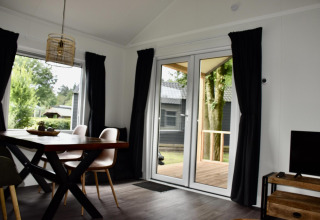 Salón moderno de casa playera con comedor y terraza en Camping 't Veld, Países Bajos.