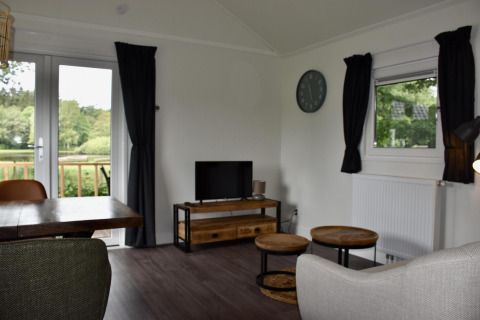 Sala de estar en Beach house con jacuzzi en Camping 't Veld, Países Bajos, vista a la naturaleza.