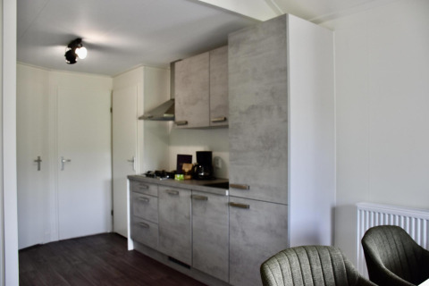 Modern kitchenette with gray cabinets inside a chalet at Beach house with hottub at Camping 't Veld, Netherlands.