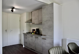 Modern kitchenette with gray cabinets inside a chalet at Beach house with hottub at Camping 't Veld, Netherlands.