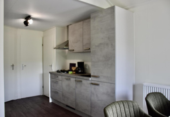Angolo cottura moderno con armadietti grigi in uno chalet di Beach house con hottub al Camping 't Veld, Olanda.