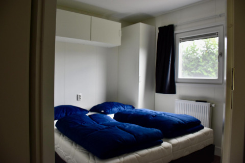 Bedroom at Beach house chalet at Camping 't Veld in the Netherlands with twin beds and blue bedding.
