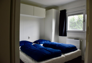 Bedroom at Beach house chalet at Camping 't Veld in the Netherlands with twin beds and blue bedding.