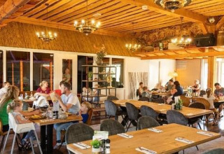 Zona interior de comedor en Beach house con jacuzzi en Camping 't Veld, Países Bajos, familias cenando.
