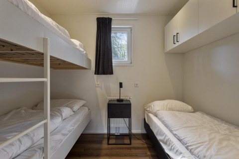 Værelse på Module Wood ved Bospark Ede, Nederlandene, med køjeseng, enkeltseng og moderne indretning.