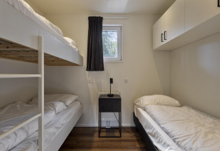 Chambre du Module Wood à Bospark Ede, Pays-Bas, avec lit superposé, lit simple et décoration épurée.