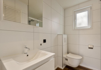 Moderne badeværelse med væghængt toilet, vask og spejl ved Module Wood i Bospark Ede, Holland.