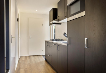 Moderne houten keuken in Module Wood-lodge, Bospark Ede, Nederland, met donkere kasten en gaskookplaat.