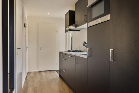 Cocina moderna de madera en la casa Module Wood, Bospark Ede, Países Bajos, con gabinetes oscuros.