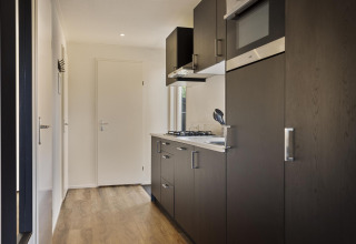 Cocina moderna de madera en la casa Module Wood, Bospark Ede, Países Bajos, con gabinetes oscuros.