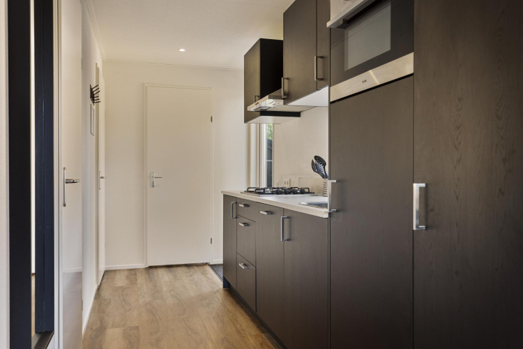 Modern wood kitchen at Module Wood lodge in Bospark Ede, Netherlands, with dark cabinets and gas stove.