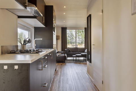 Cocina y sala modernas con ventanas grandes en la lodge Module Wood de Bospark Ede, Países Bajos.