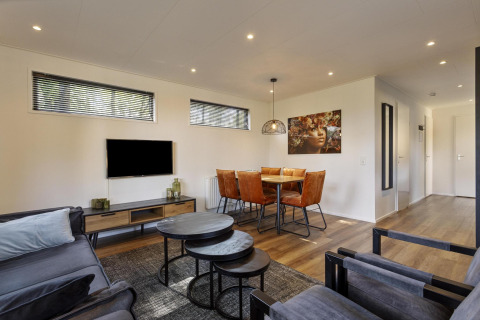 Soggiorno e sala da pranzo moderni nella lodge Module Wood a Bospark Ede, Paesi Bassi, con arredi eleganti.